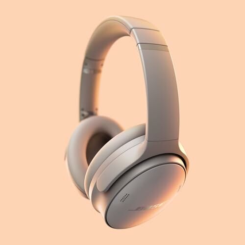 Gray wireless headphones on a peach background